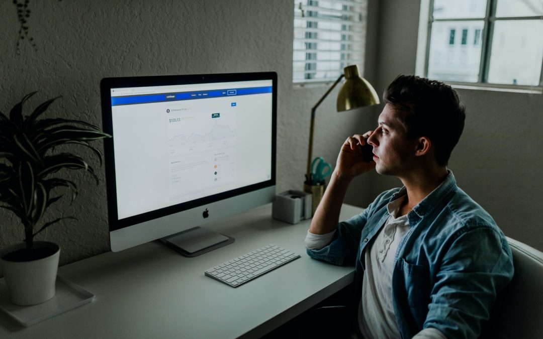 man sitting a desk in front of Mac computer on a phone looking for work upgrade cover letter