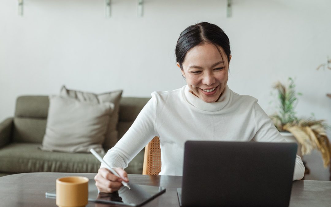 woman working at home on a laptop while taking notes